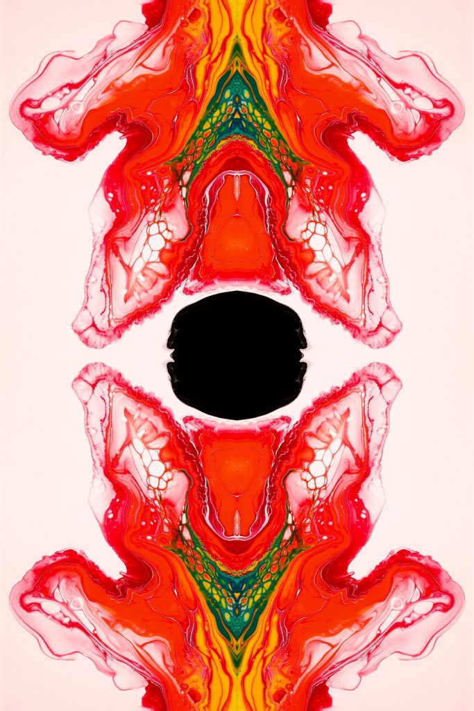 A photo of a a red and yellow abstract painting with a black hole in the center.