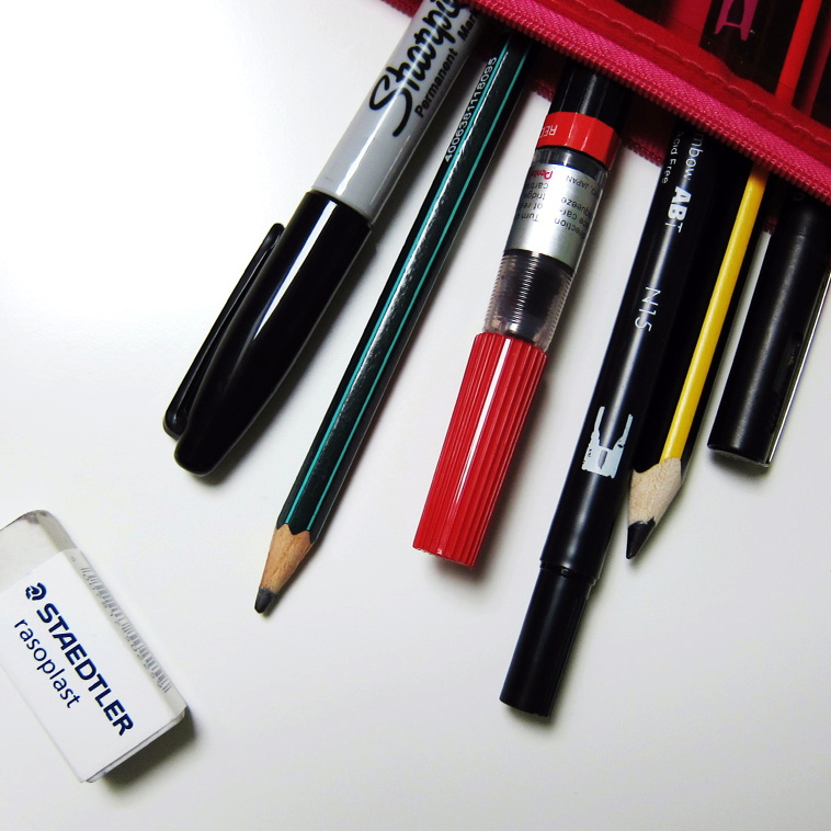 writing instruments spilling out of a red pencil holder